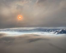 Scientists on a NASA-flown DC-8 were able to photograph and view this wildfire-produced thunderstorm. Layers of smoke in the atmosphere near the thunderstorm make the sun appear orange. (Photo courtesy of David Peterson, Naval Research Laboratory)